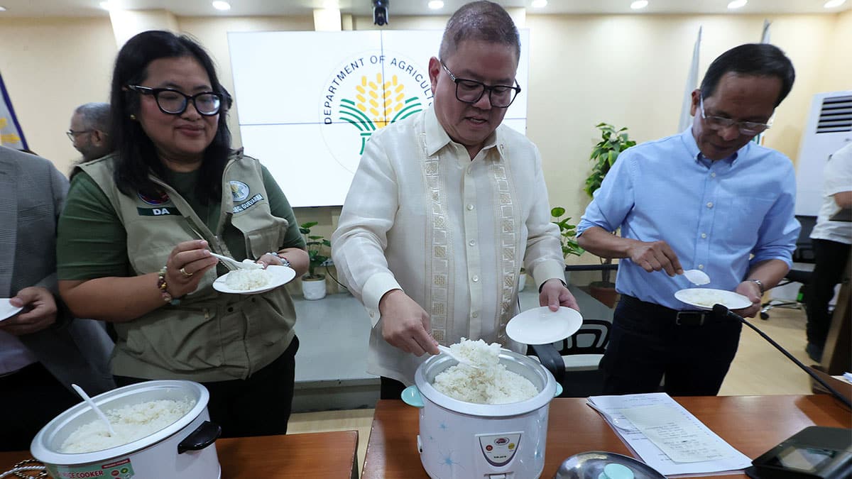 TASTE TEST AgricultureSecretary Francisco Tiu Laurel Jr. (center) samples the P20- per-kilo rice on Tuesday inQuezon City to dispel doubts about the quality of stocks sold that cheap. —GRIG C.MONTEGRANDE